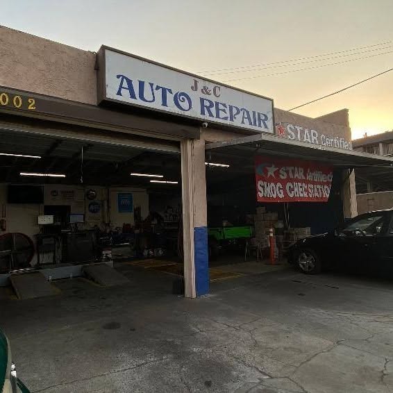 J & C Auto Repair sign and STAR smog banner at dusk